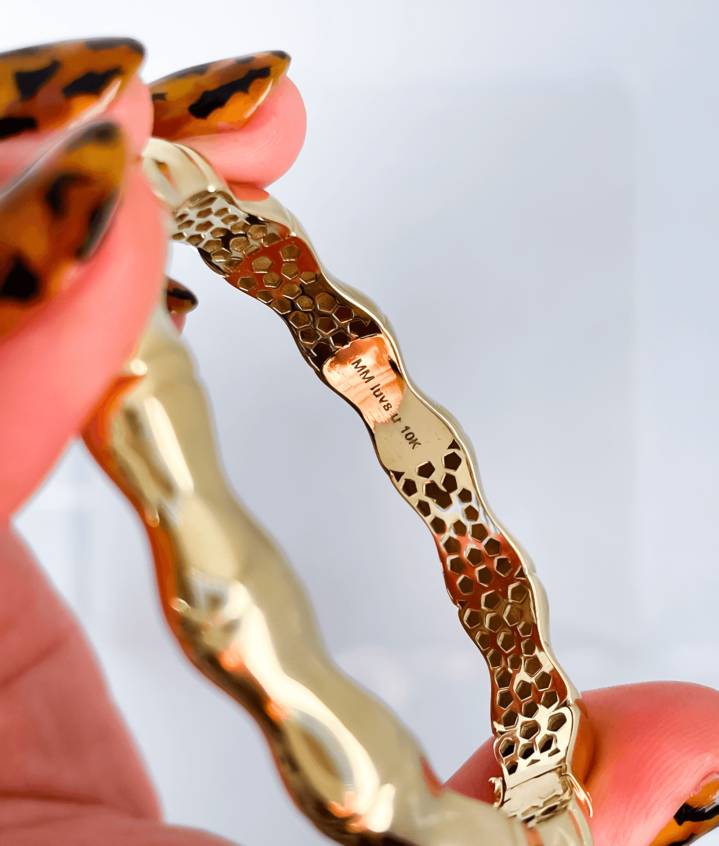 Black woman's hand, leopard print manicure holding bamboo bangle