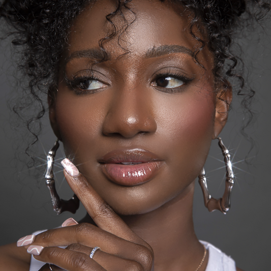 Black Model with pink nails wearing white gold oval shape bamboo earrings and diamond eternity band ring