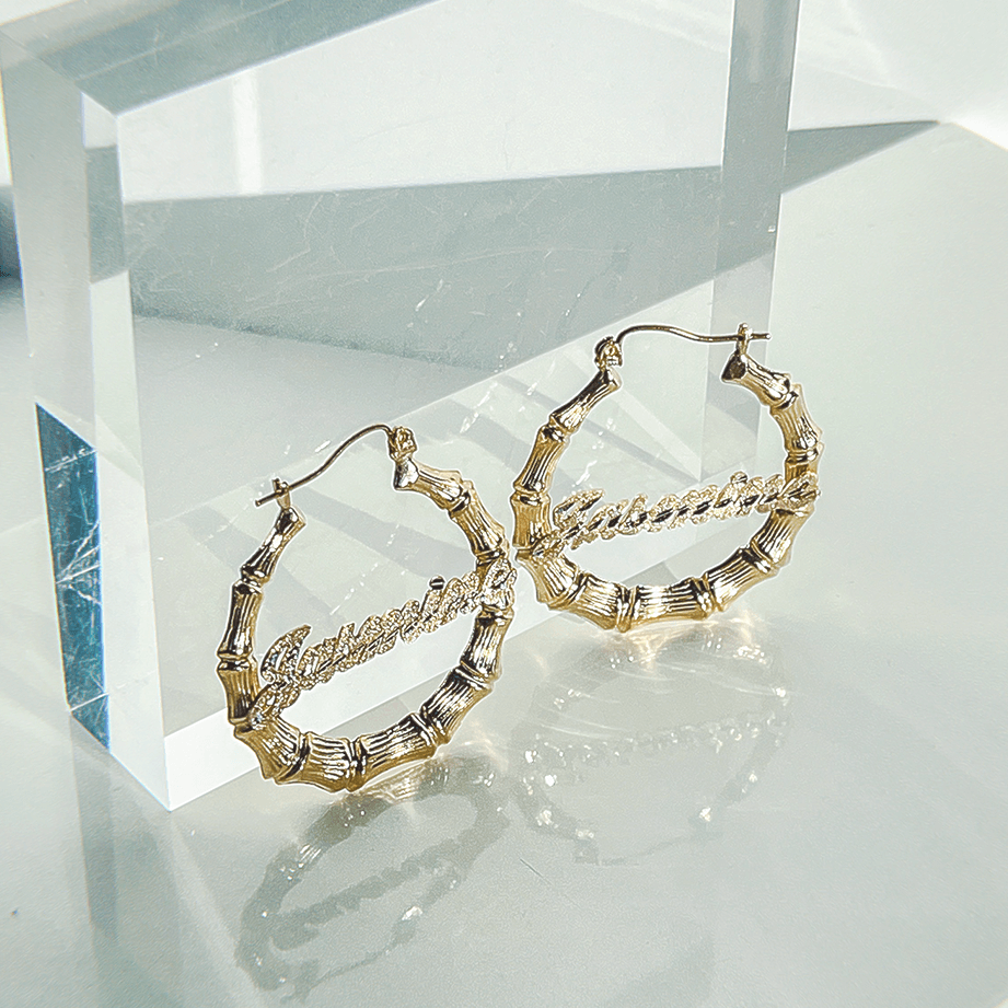 Real Gold Earring with Name on it leaning on clear acrylic cube