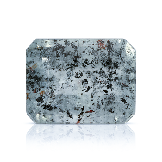 Emerald-cut Leopard Aquamarine gemstone with hematite and iron inclusions on a white reflective background.